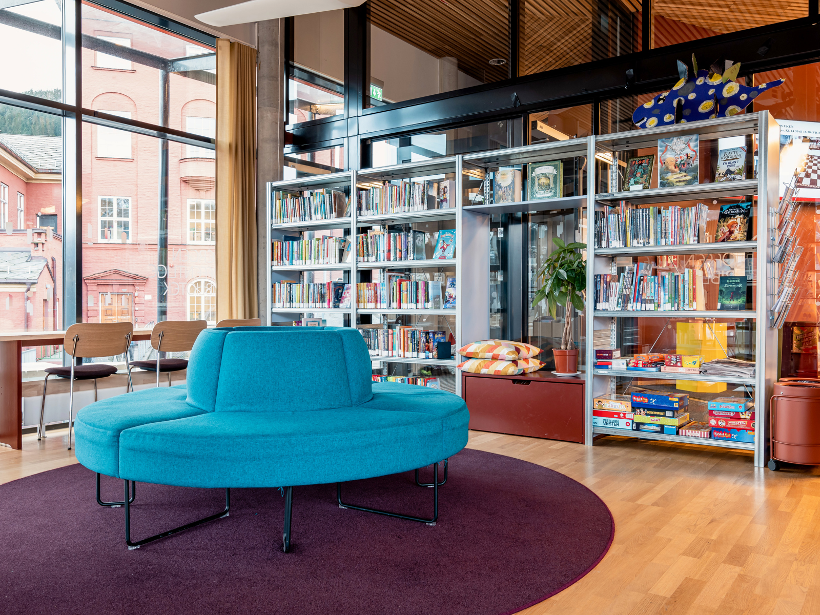 Interiør foto av bibliotek, rund blå sofa midt i rommet.