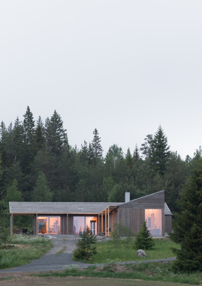 Eksteriørfoto av enebolig med trekledning omgitt av skog.