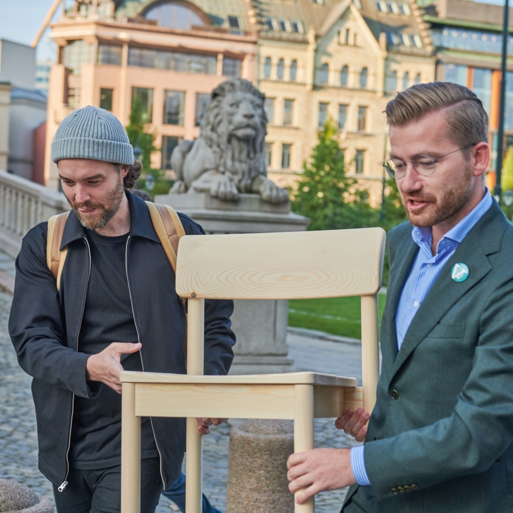 Bilde av designer og daværende miljøminister Sveinung Rotevatn (V) bære Nuen-stolen utenfor Stortinget.