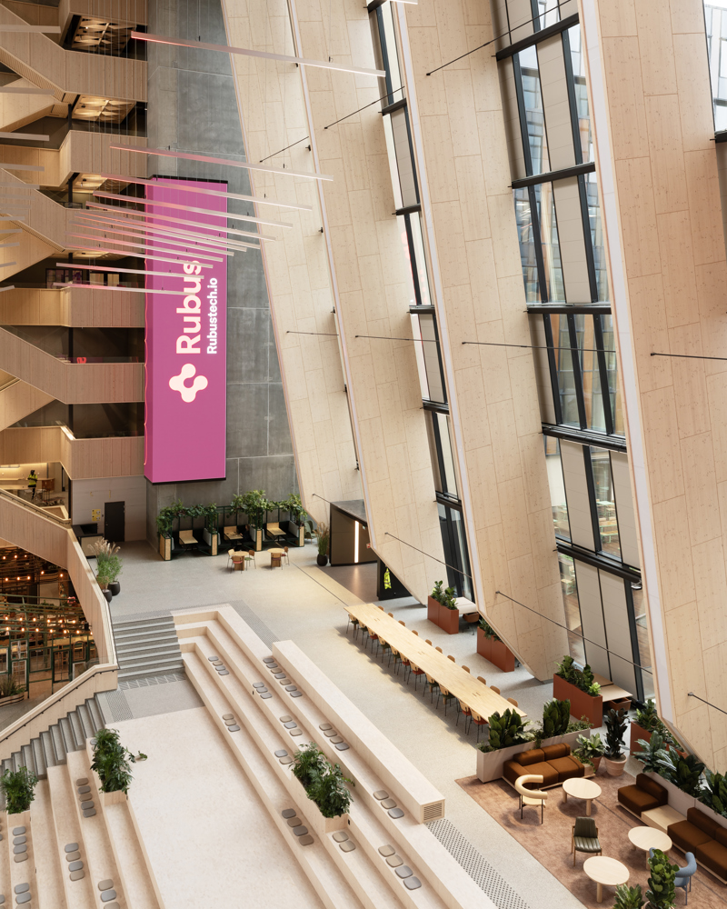 Interiør foto av fellesareal i kontorbygg med limtrekonstruksjon og stor takhøyde.