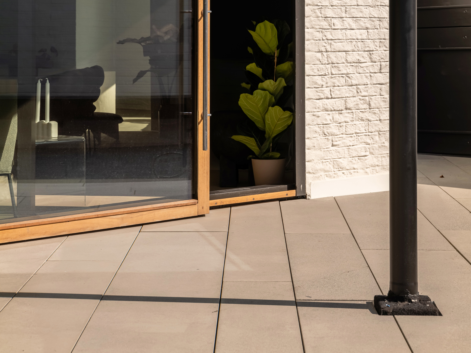 Foto av skyvedører i glass utenfra, stål søyle i forgrunnen, stue innenfor døren.