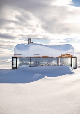 Et bygg i treverk med store vinduer nedsnøet i et vinterlandskap. Foto.