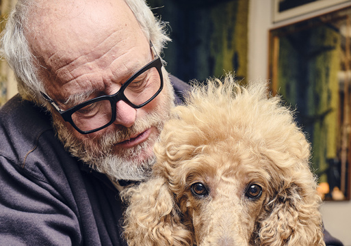 Portrett av Erling Okkenhaug holder rundt en puddel. Foto.
