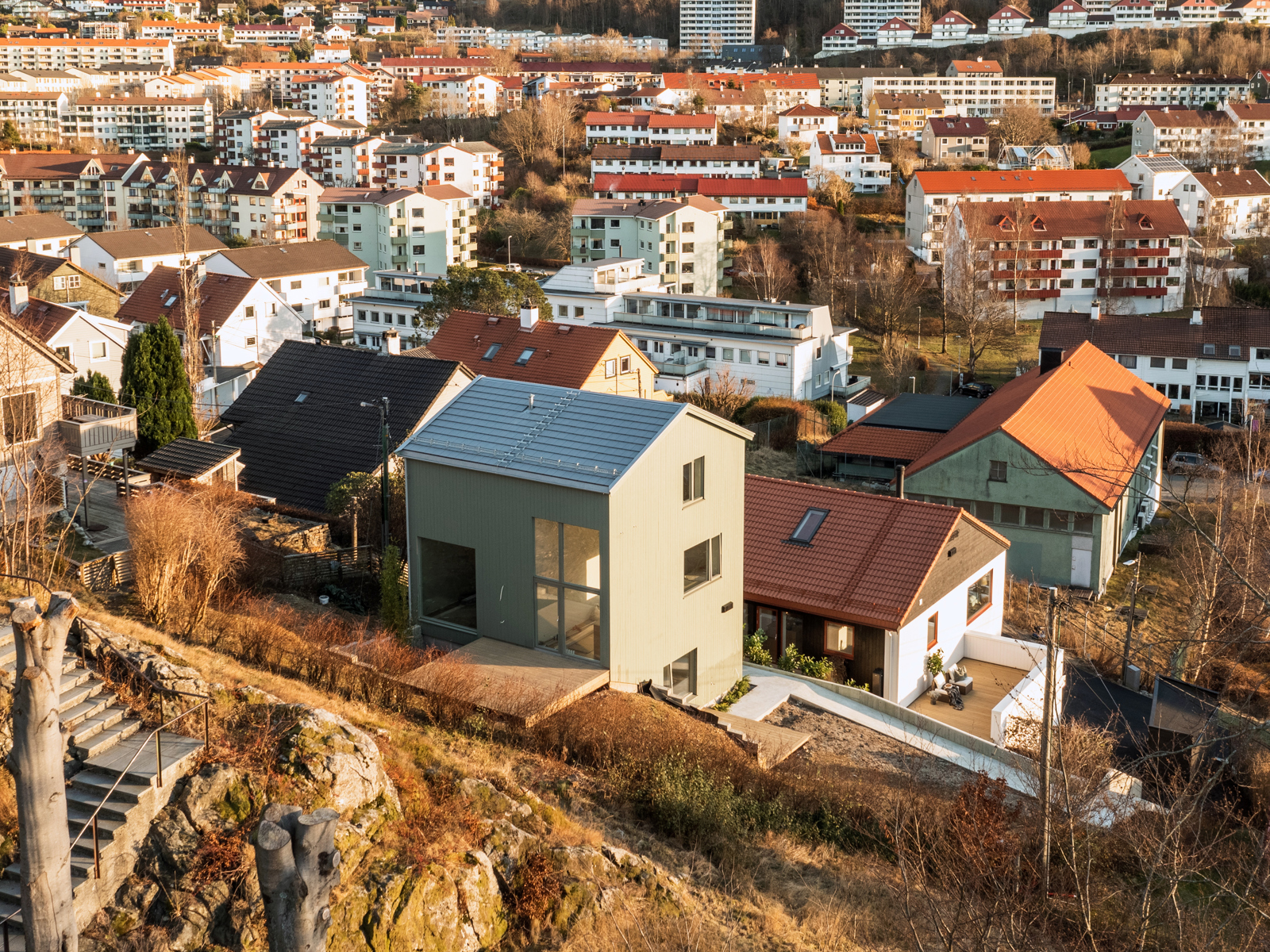 Foto av bolig i nabolag kontekst, høstfarger og en ås i bakgrunnen.