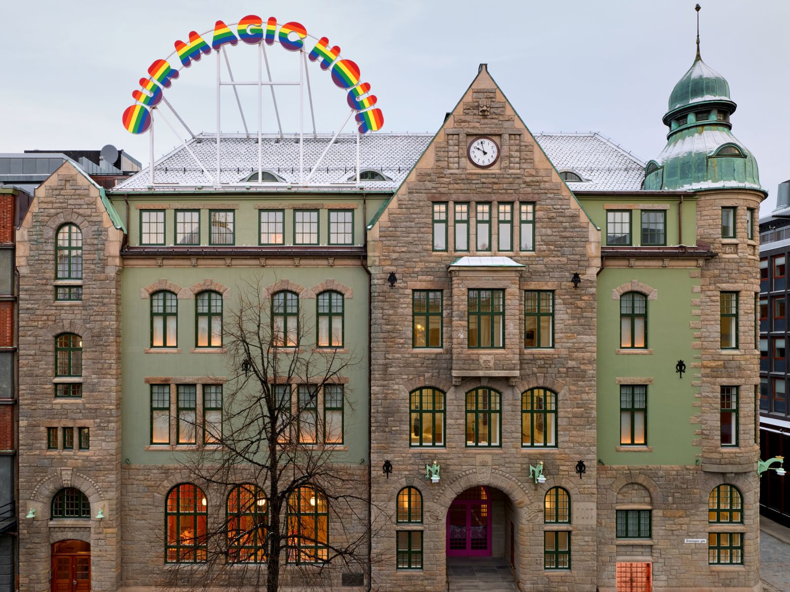 Fasade foto av bygg i jugendstil med et skilt på taket i regnbuefarger.