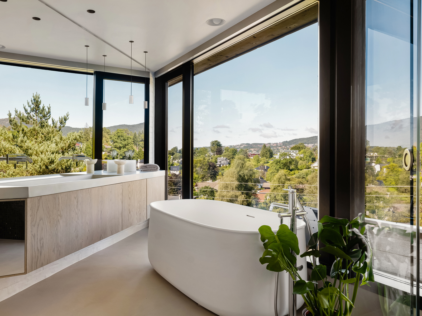 Interiør foto av baderom med glass i alle vegger, badekar og lang benk med vask.