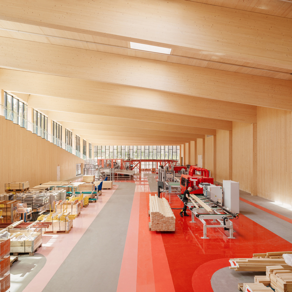 Interiør i treverk og rødfarger på gulv. Fabrikkhall. Foto.