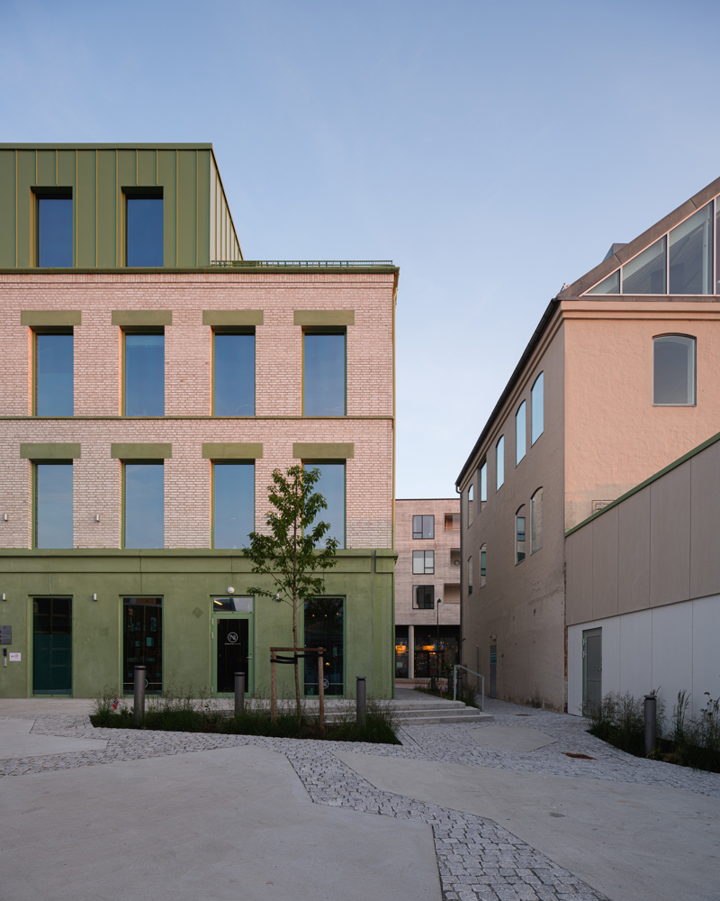 Foto av fasaden på et murgårdsbygg med grønne betong detaljer.