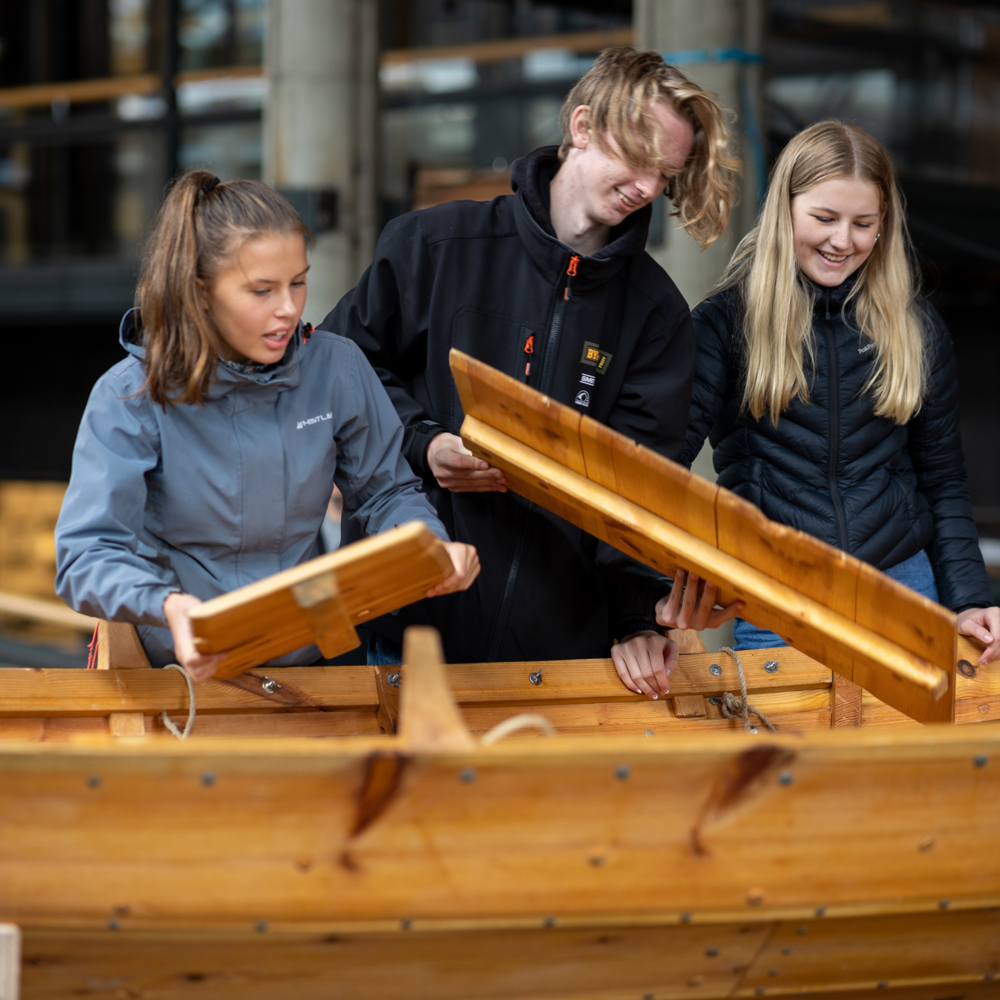 Tre båtbyggere over en trebåt