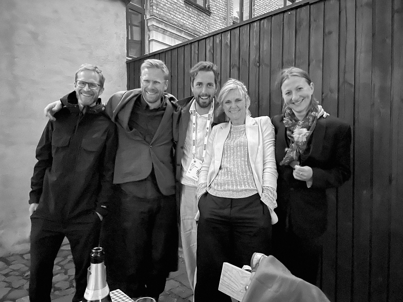 Gruppefoto av fem voksne mennesker utendørs, svart hvitt foto.