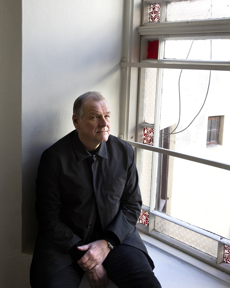 Portrett av Atle Aas som sitter i en vinduskarm. Foto.