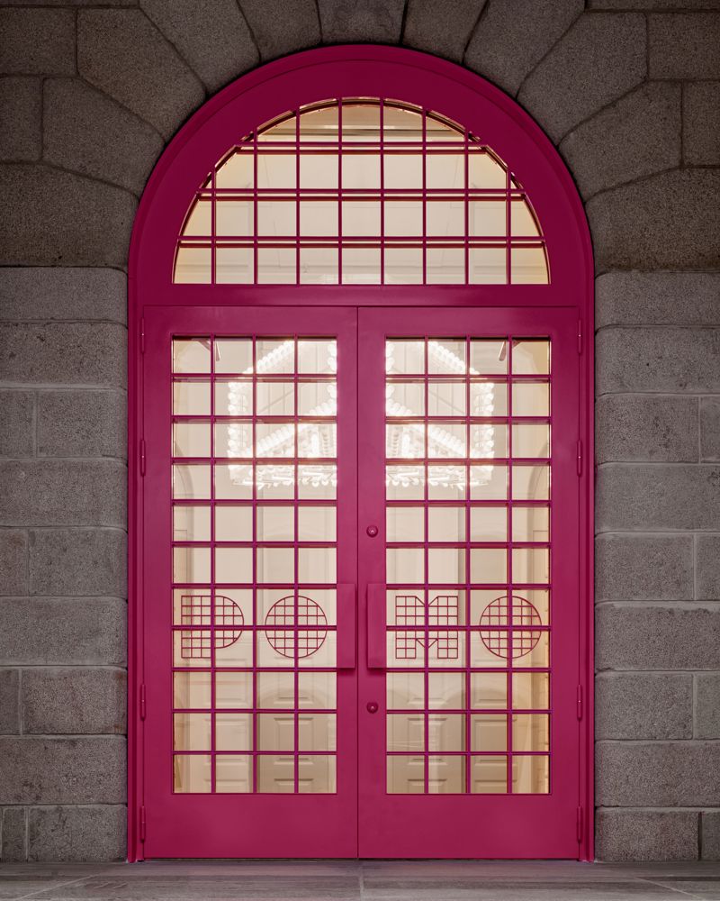 Foto av rosa dør med buet topp karm.