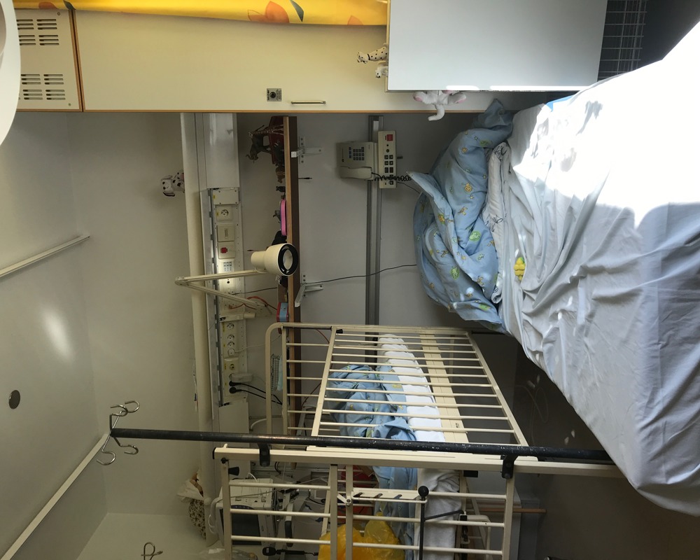 Foto av et sykehusrom med en madrass på gulvet og en sykehus sprinkelseng.