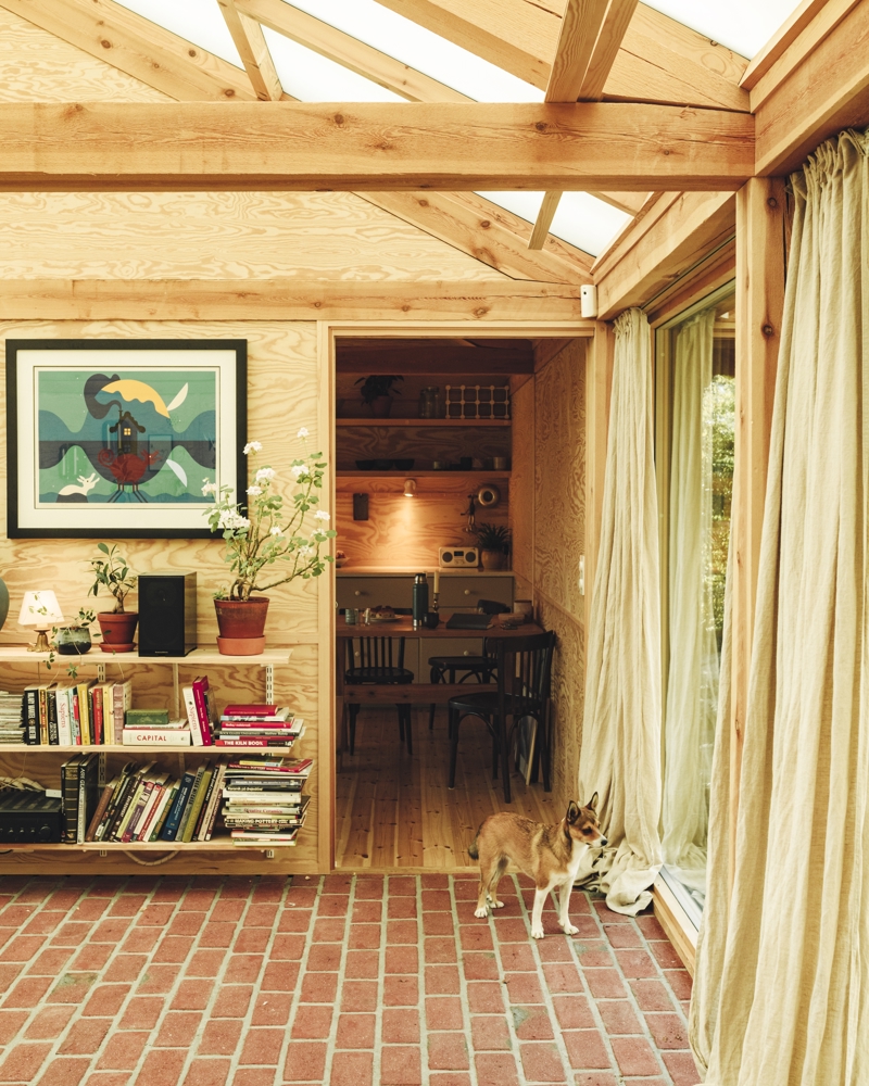 Interiør foto av rom meg tegl gulv og vegger i treverk. Hund ser ut av vinduet.