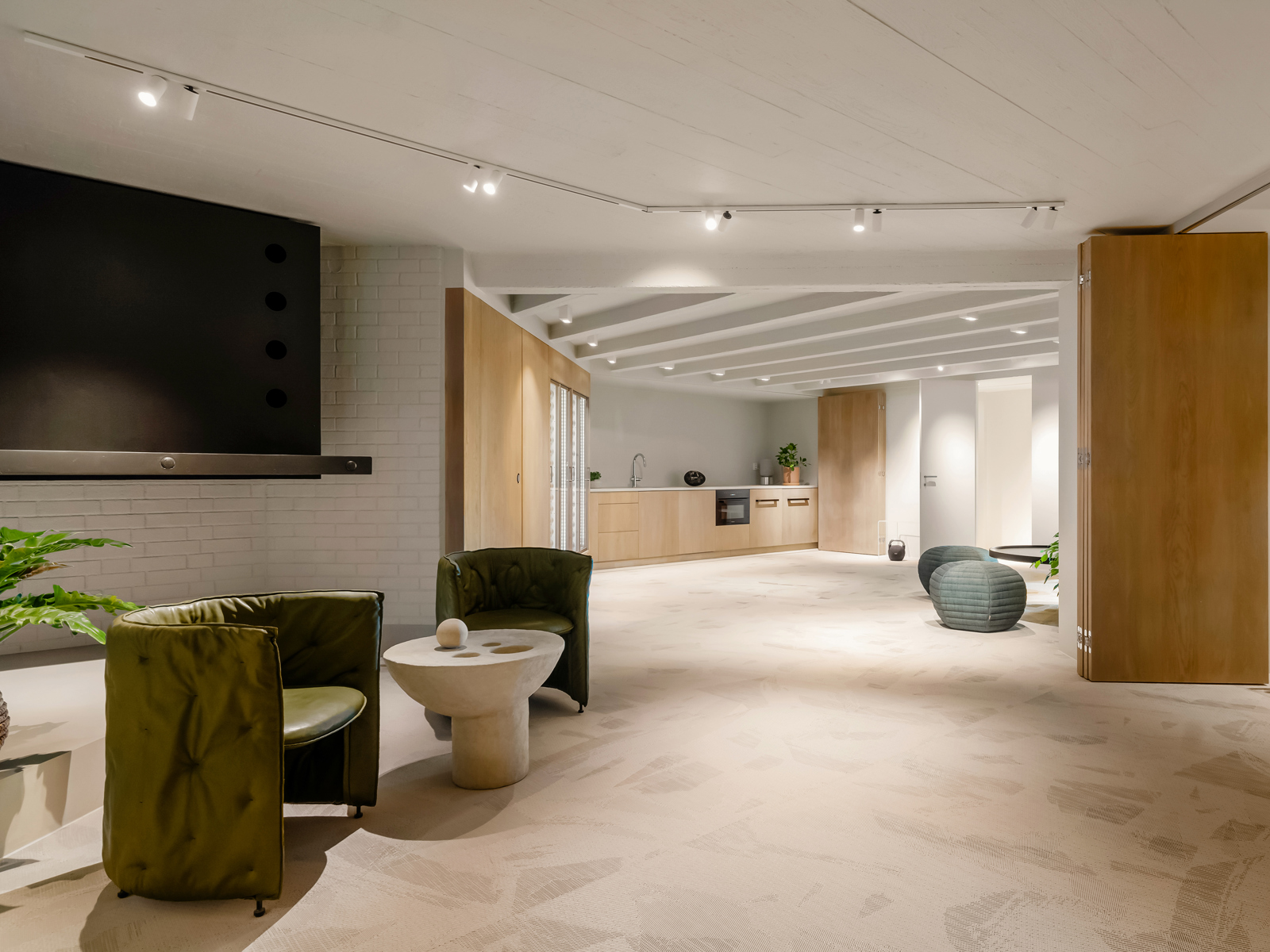 Interiør foto av oppholdsrom med flere sittegrupper og en kjøkkenbenk bakerst i rommet.