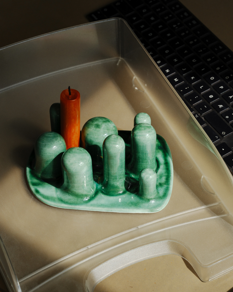 Foto av en grønn lysestake med et rødt lys.