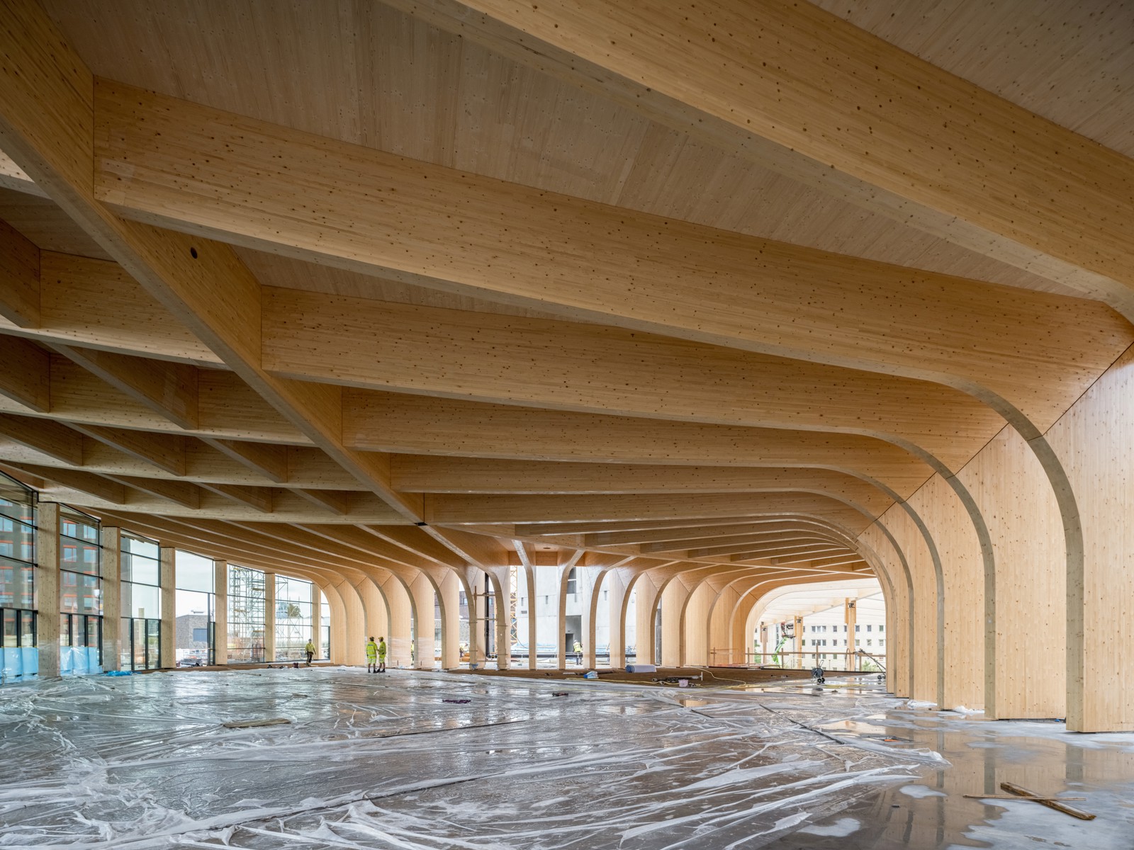 Byggeplass interiør, stort rom med trebjelker og tresøyler i limtre. Foto.