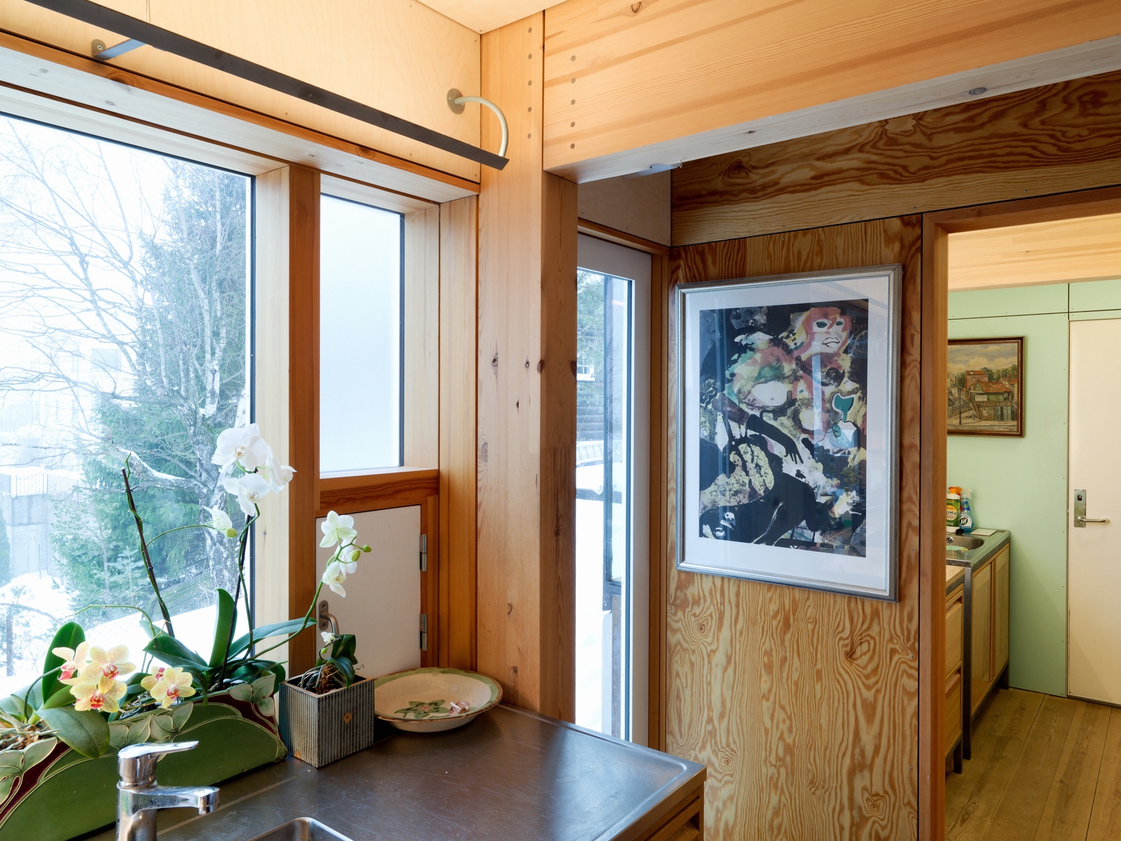 Interiør foto av kjøkken med kunst på veggen og ulike materialer og farger på veggene.