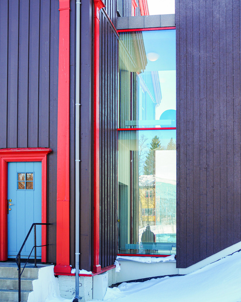 Eksteriørfoto av trehus, inngangsdør og glassfasade.
