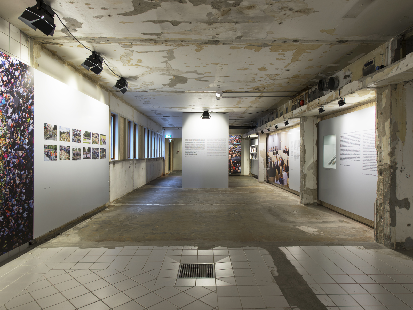 Interiør, utstillingsrom, slitte vegger, gulv og søyler. Hvite felter der elementer er stilt ut. Foto.