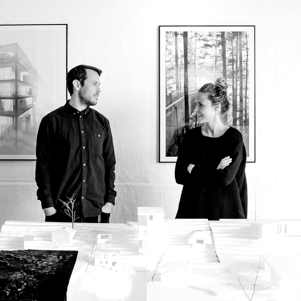 Sanden+Hodnekvam står bak et bord med en arkitekturmodell. Foto.