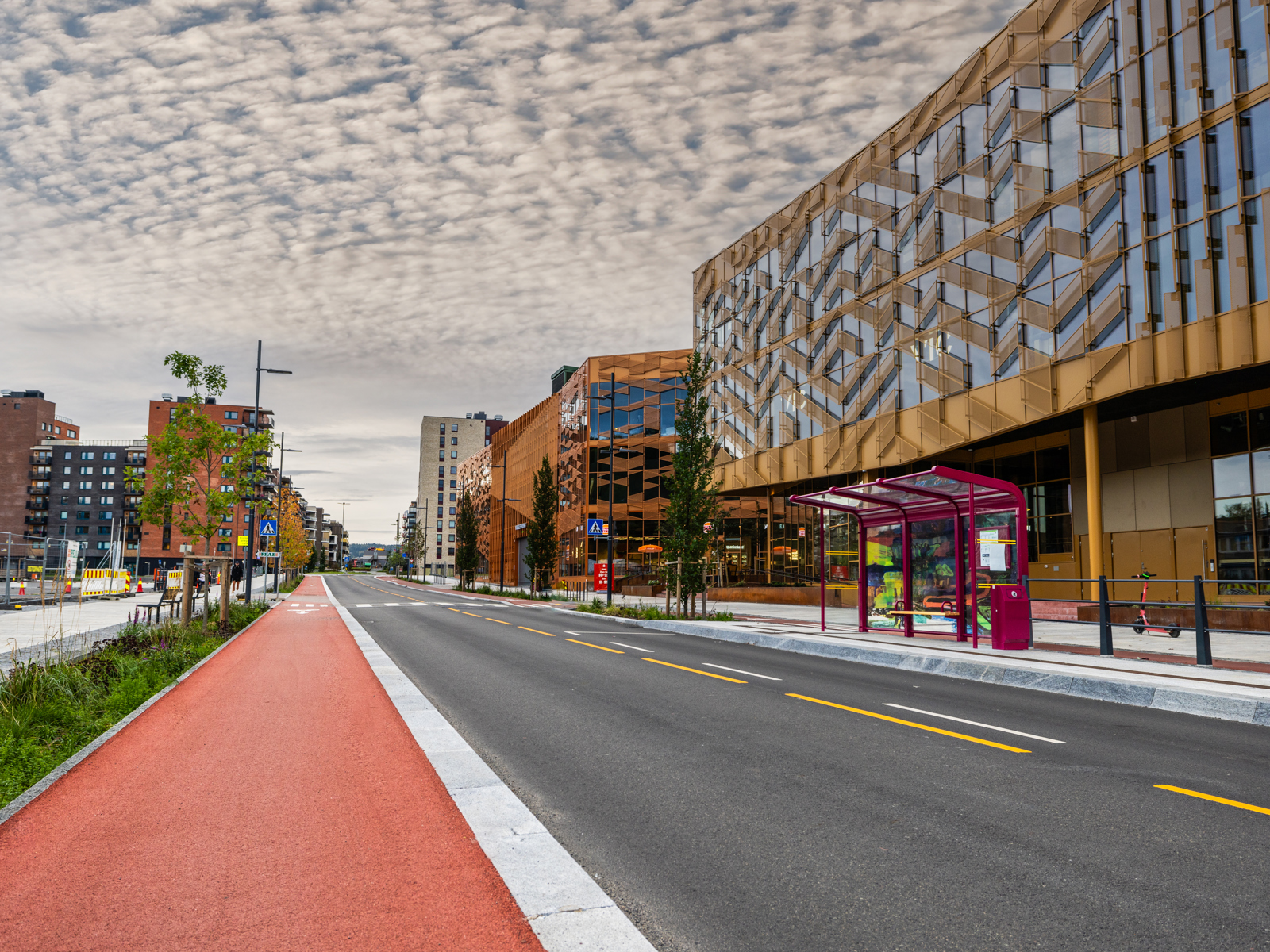 Foto av gateløp med rødt sykkelfelt, bilvei og blokker på høyre side.