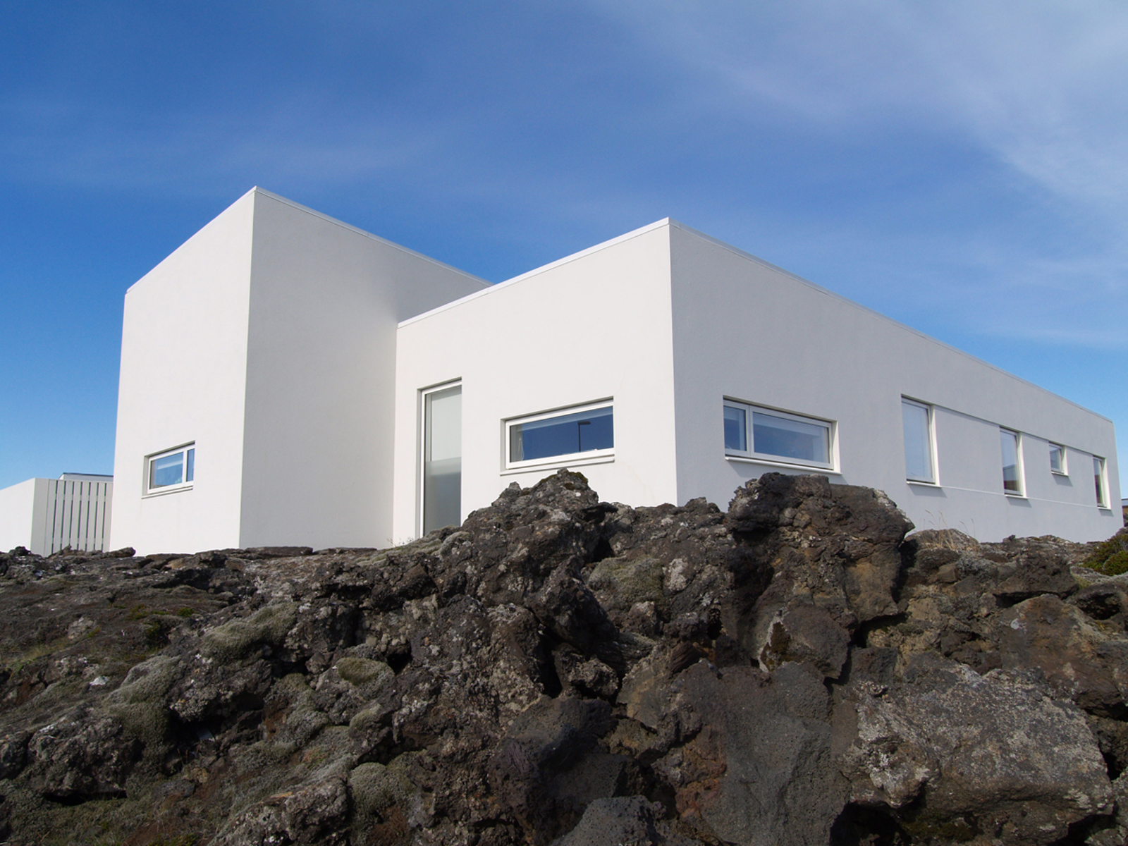 Foto av Hvitt moderne bolighus på fjellgrunn.