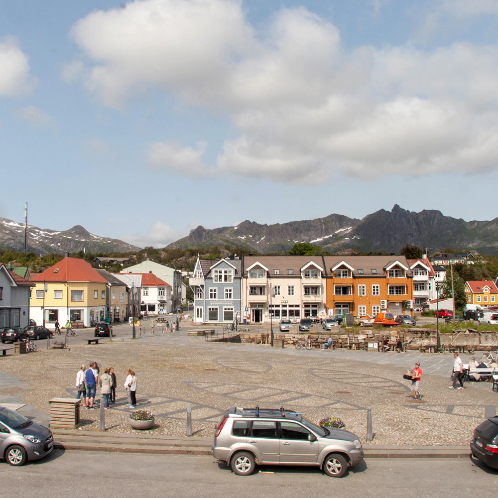 Foto av en tom plass i Kabelvåg med små trehus rundt