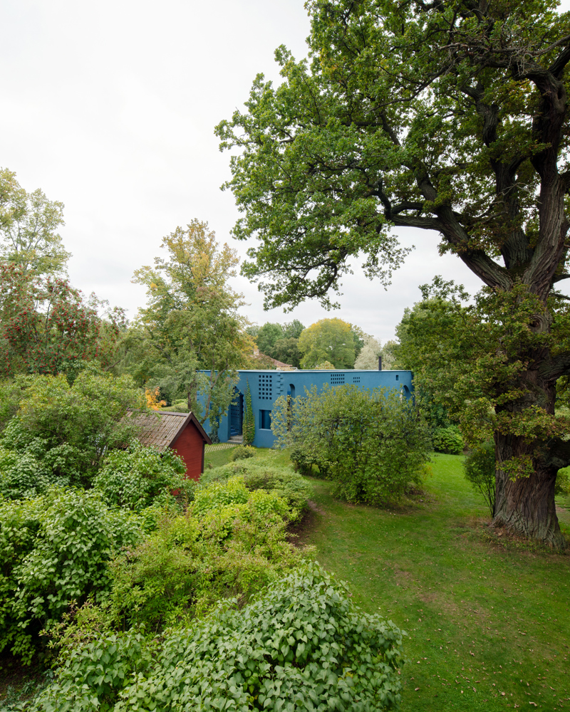 Foto av et blått hus i en grønn hage.
