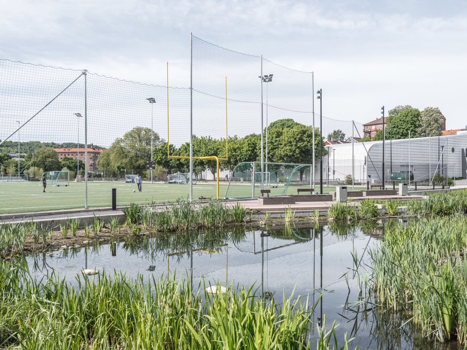 Fotballbane i bakgrunnen, vann i forgrunnen. Foto.