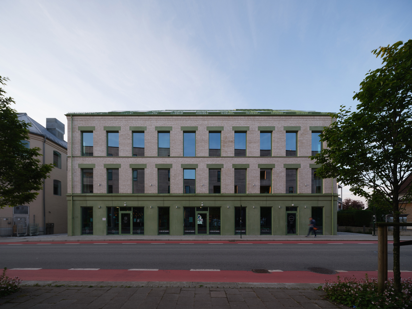 Foto av en mursteinsbygg med grønne betong detaljer og tak.