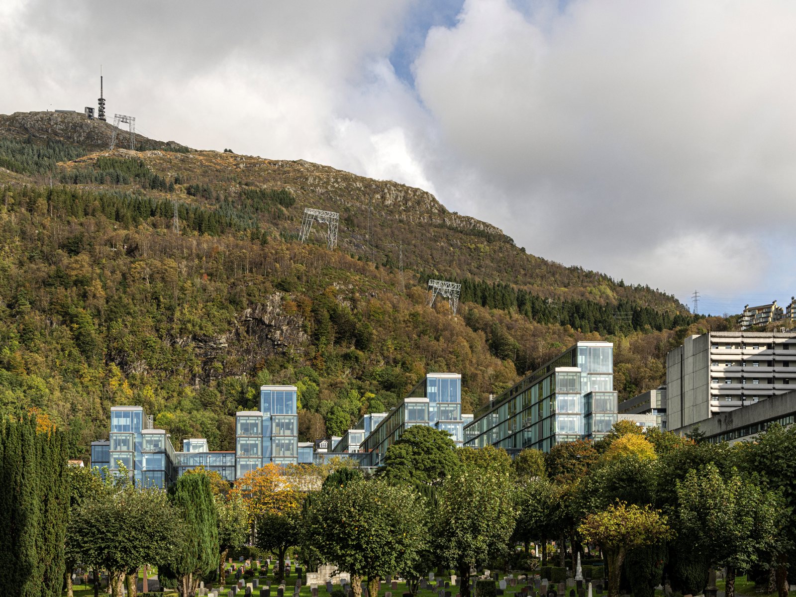 Foto av Glasblokkene med trær og vegetasjon i forgrunnen, og fjellet Ulrikken i bakgrunnen.