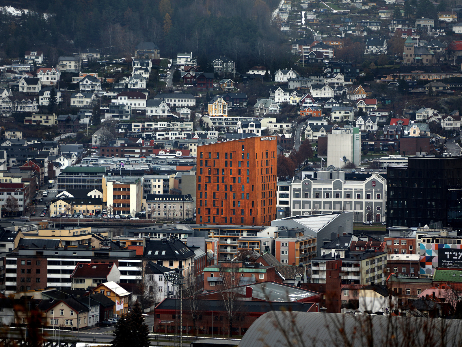 Høyt hotell i treverk i bysituasjon. Foto.