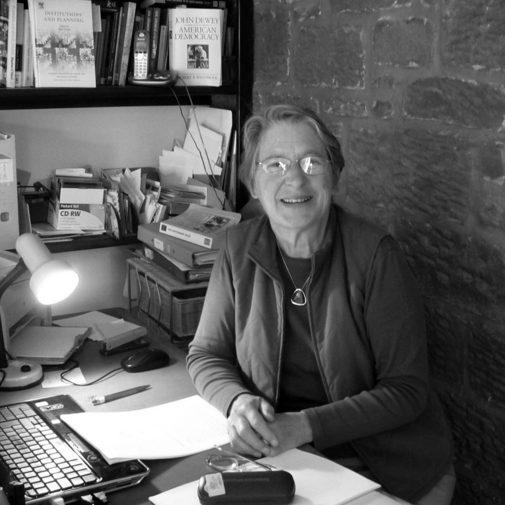Portrett av Patsy Healey sittende ved et skrivebord, svart hvitt.