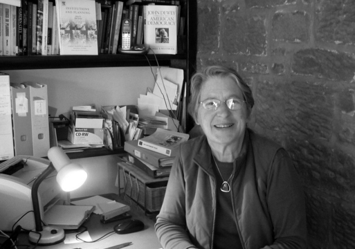 Portrett av Patsy Healey sittende ved et skrivebord, svart hvitt.