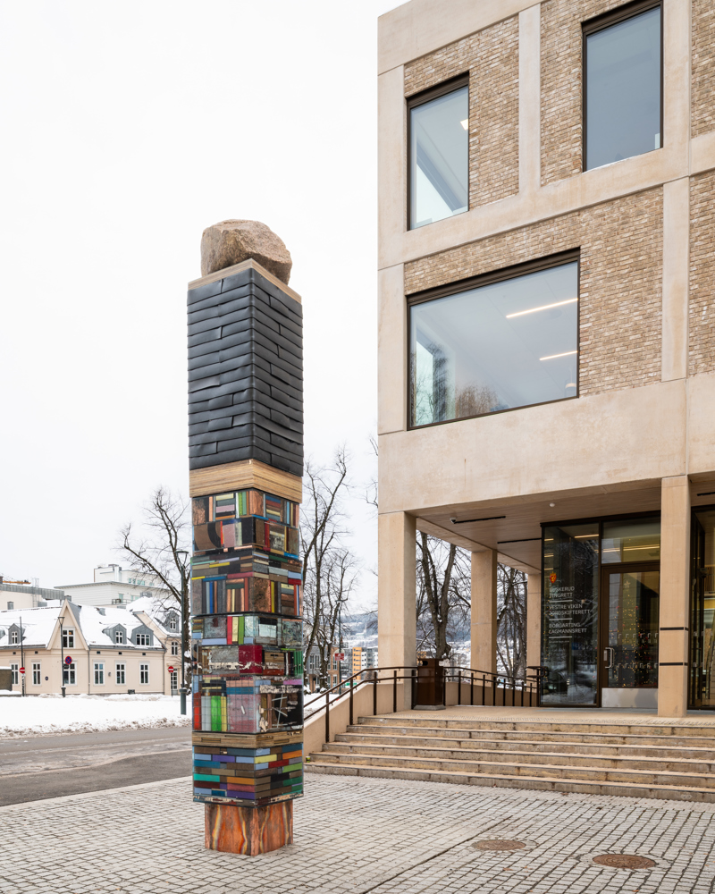 Foto av skulptur utenfor inngangspartiet til Drammen tinghus, forestiller stablede bøker. 