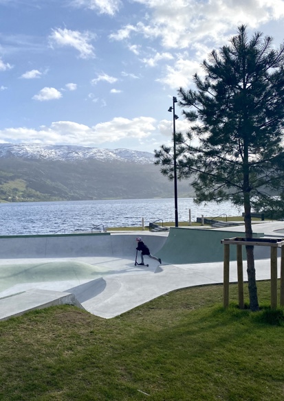 Foto av skatepark, vann og fjell i bakgrunnen. 