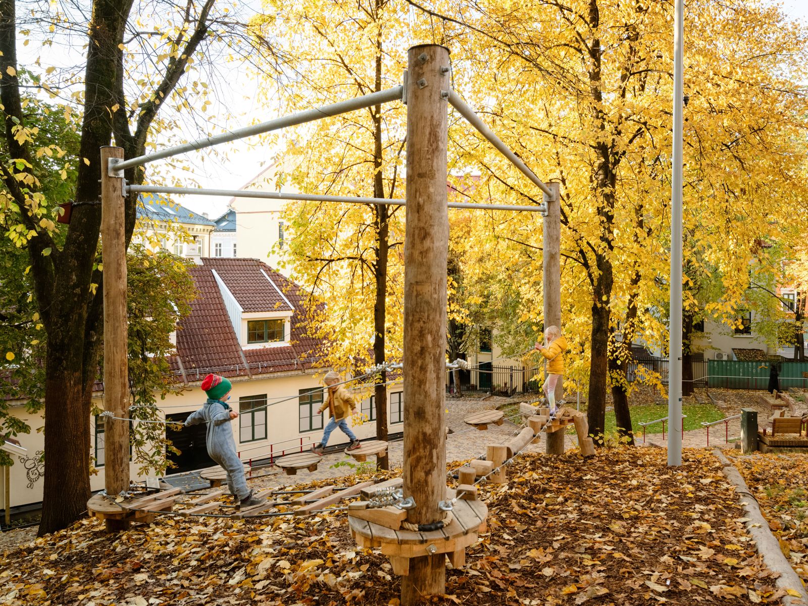 Foto av barn som leker på lekestativ i en park på høsten.