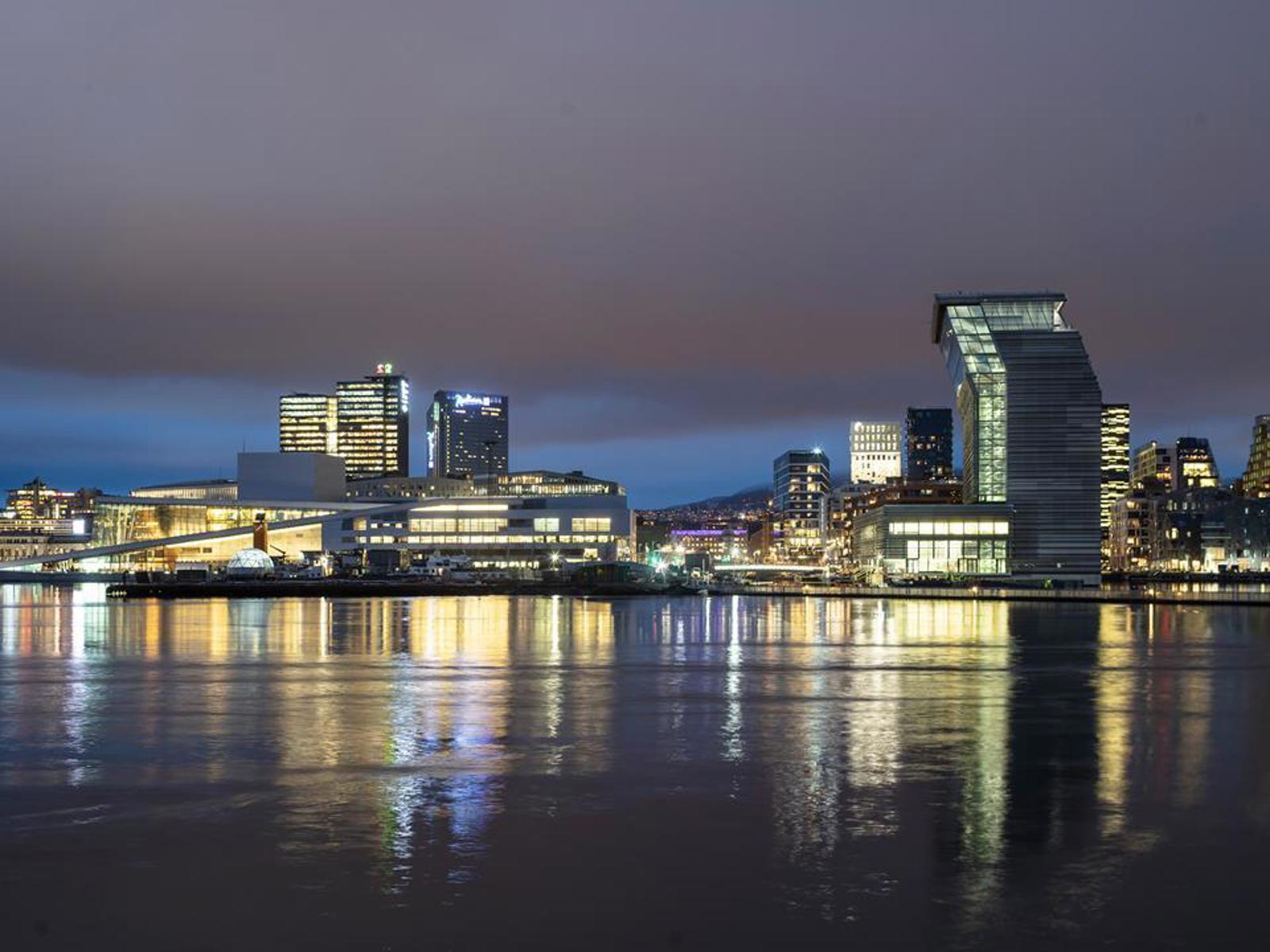 Kveldsbilde av Bjørvika, der man ser hus som operaen og Munch museet lyser opp. Foto.