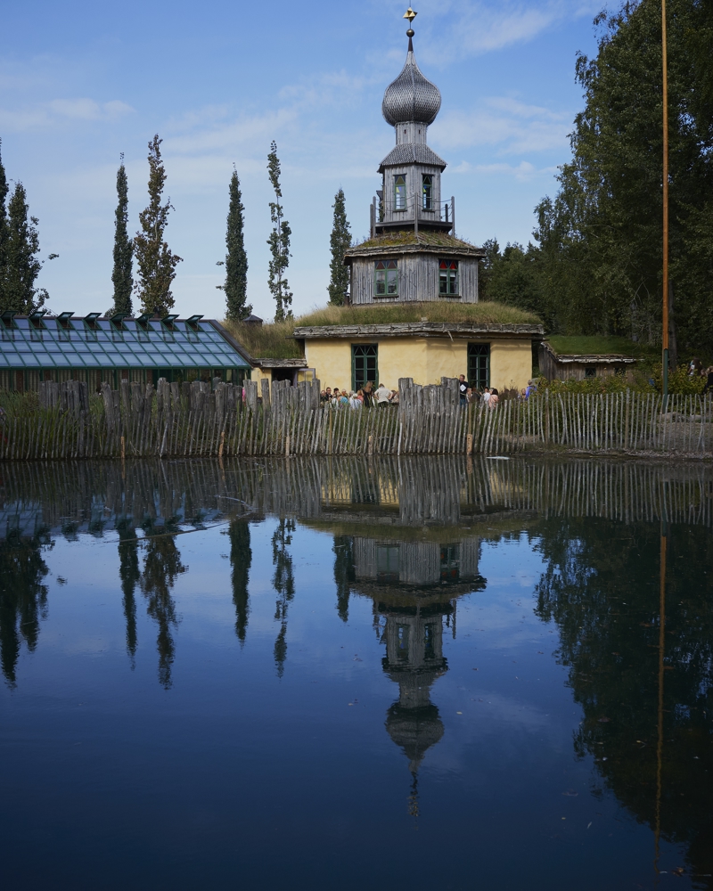 Vann inngjerdet, et hus med flere etasjer opp i et tårn i bakgrunnen. Foto.