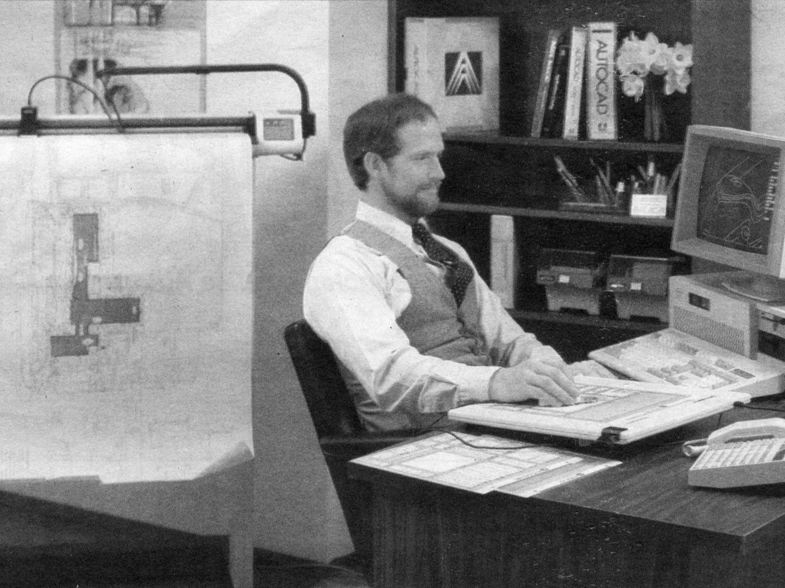 Mann sitter og jobber på en datamaskin i 1987. Svart hvitt foto.