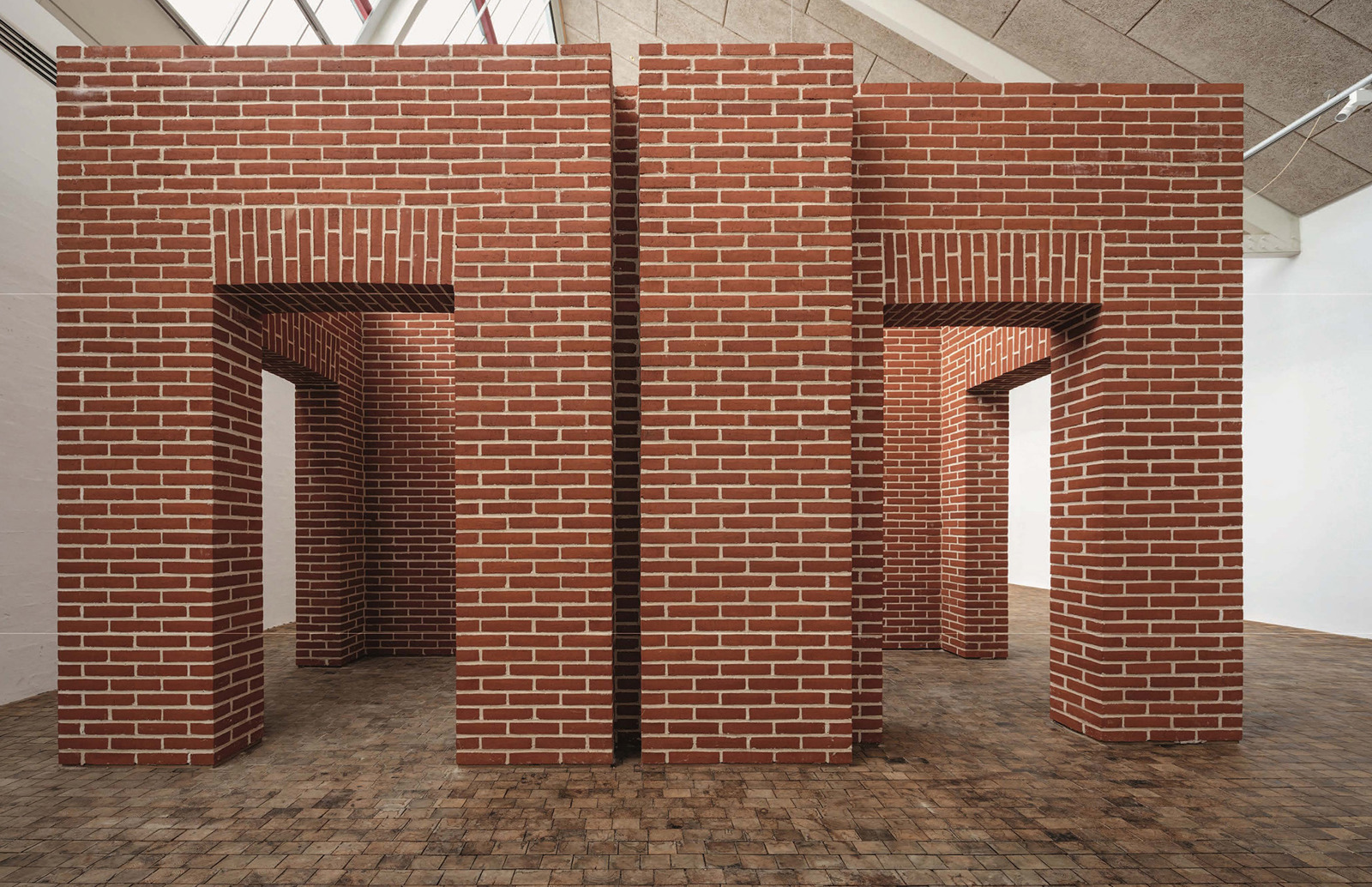 Foto av murte vegger med åpninger i rød teglstein i et utstillingsrom.