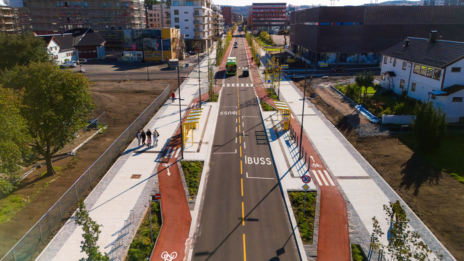 Oversikts foto av gateløp ovenfra med rødt sykkelfelt, bilvei og blokker på sidene.