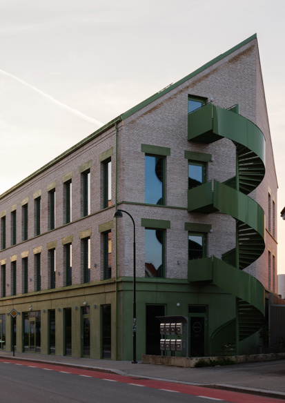 Foto av et mursteinsbygg med grønne detaljer sett fra gate.