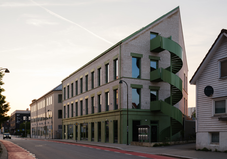 Foto av et mursteinsbygg med grønne detaljer sett fra gate.