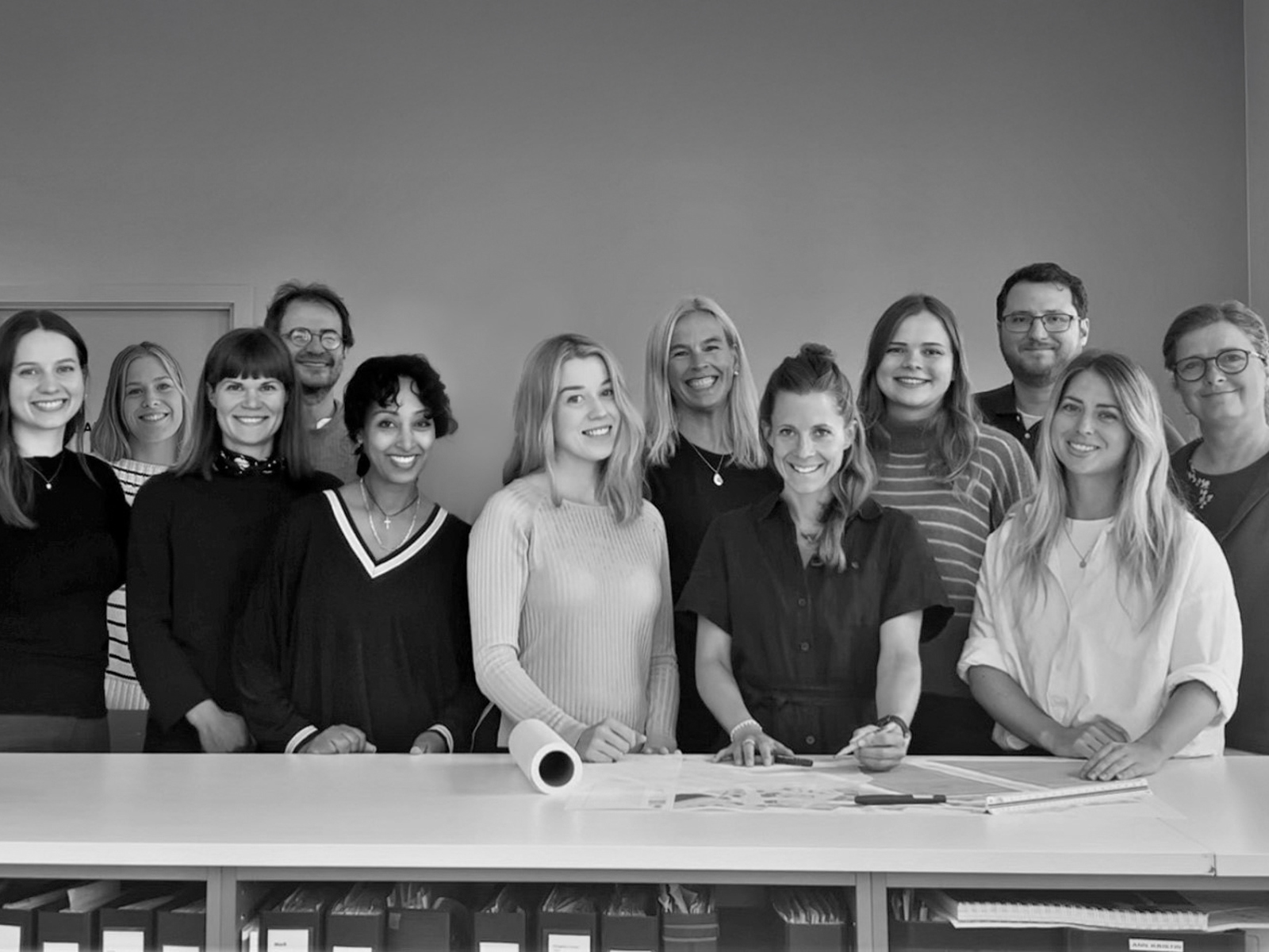 Gruppebilde av alle i Østengen & Bergo stående fremfor et langt hvitt bord.