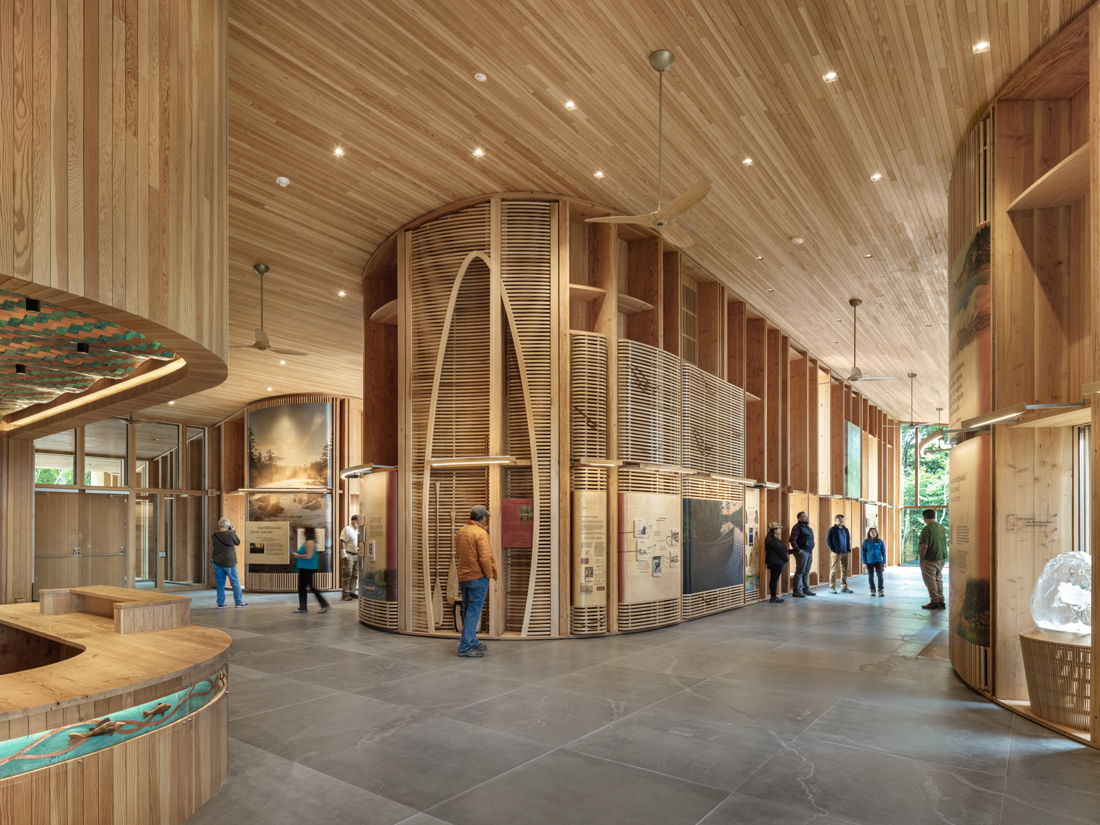 Interiør foto av Tekαkαpimək Contact Station, skranke, kunstutsilling, folk som går rundt. 