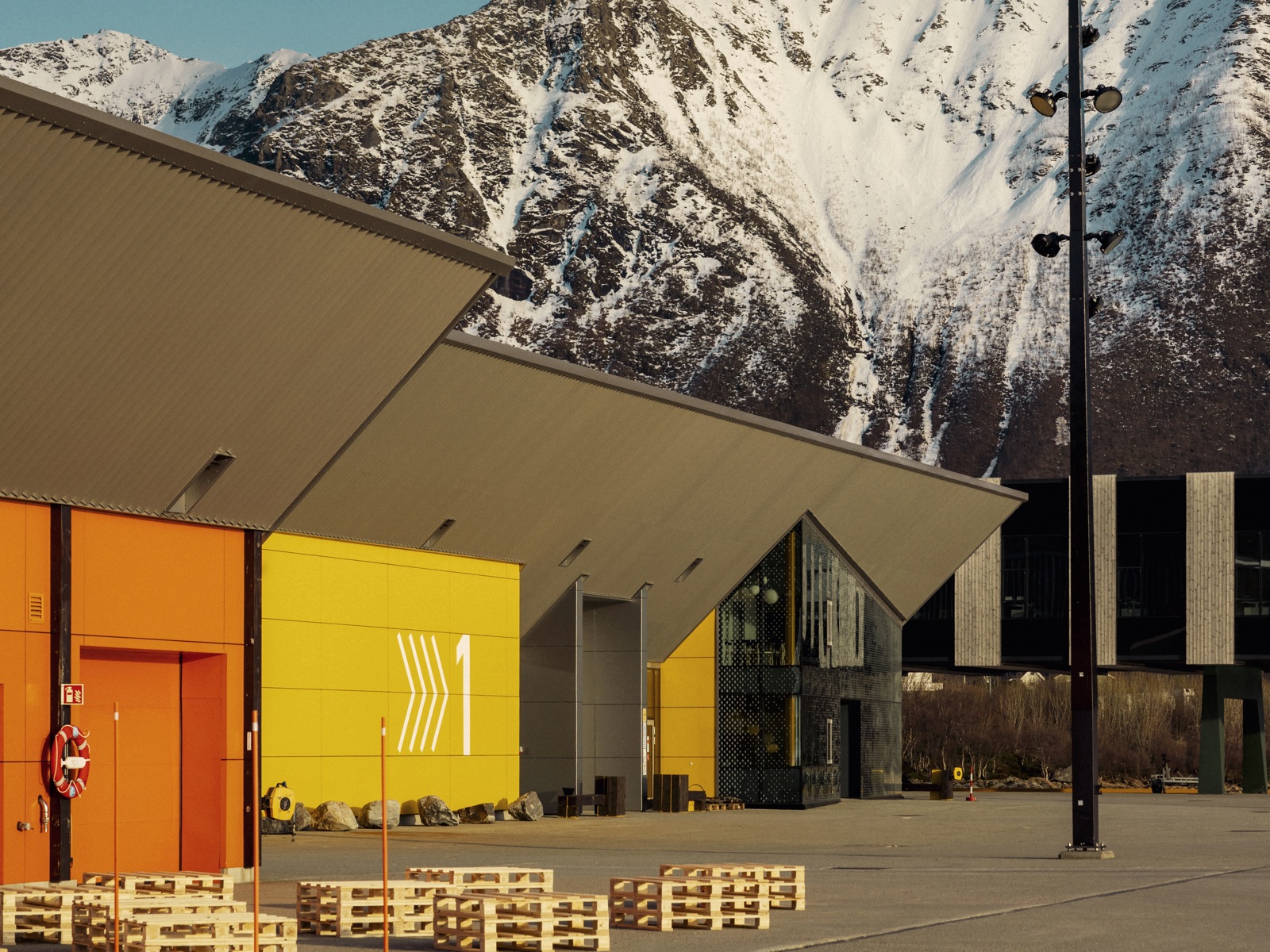 Eksteriørfoto av anlegget som viser et gult og et orange bygg, mens et snødekket fjell stekker seg opp i bakgrunnen