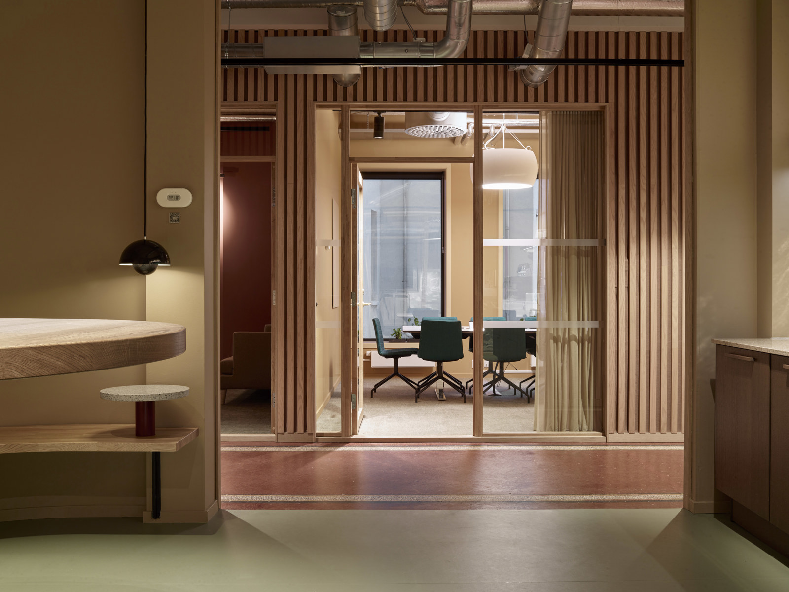 Interiørfoto som viser kontorlokaler i rødlige farger. 