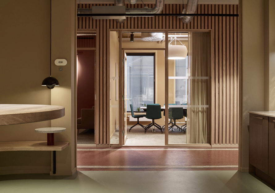 Interiørfoto som viser kontorlokaler i rødlige farger. 